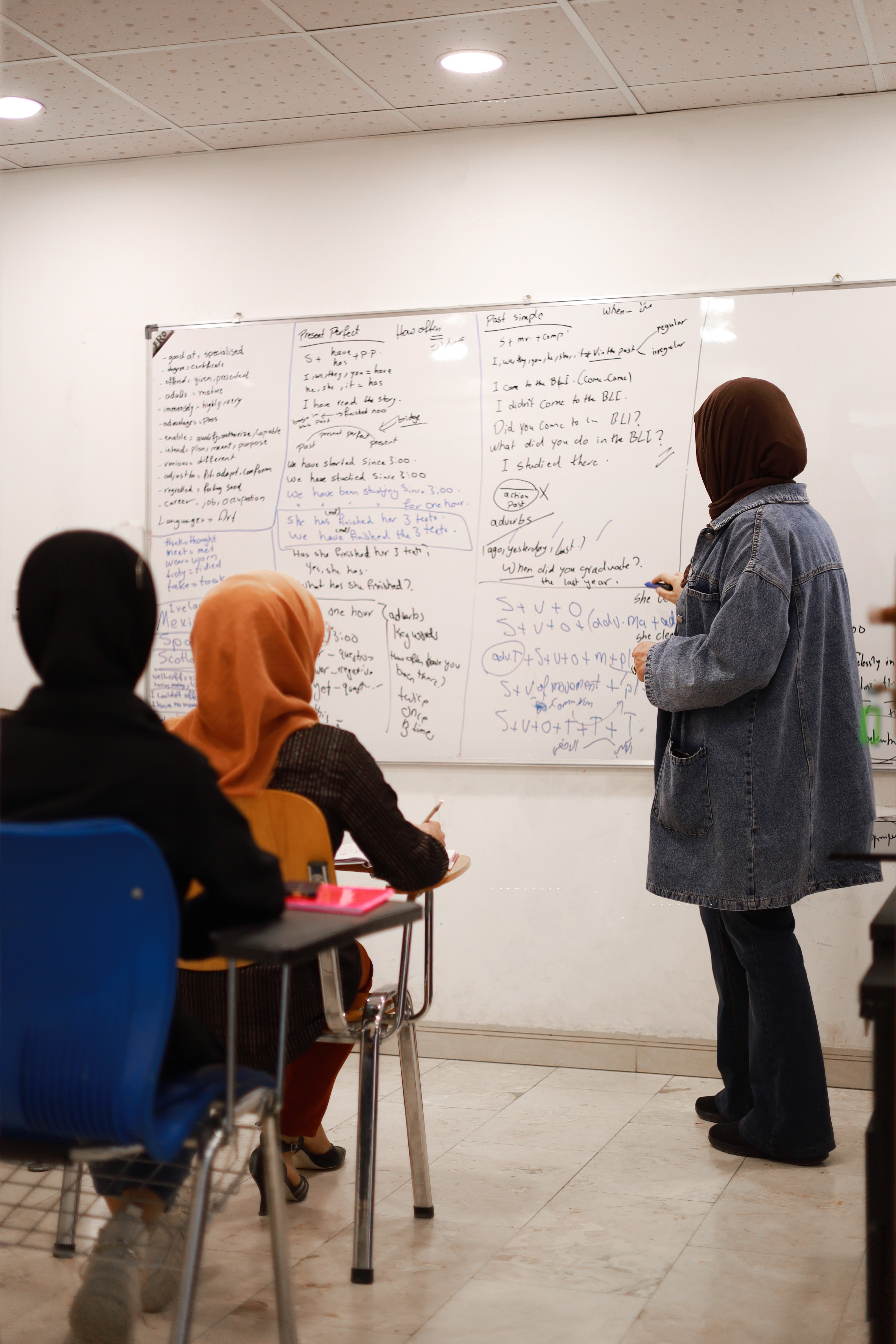 مدرّسة تشرح قواعد اللغة الإنجليزية على السبورة