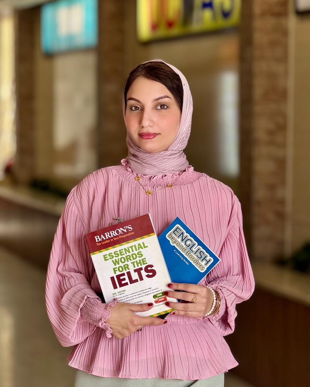 طالبة تحمل كتب التحضير لامتحان الآيلتس
