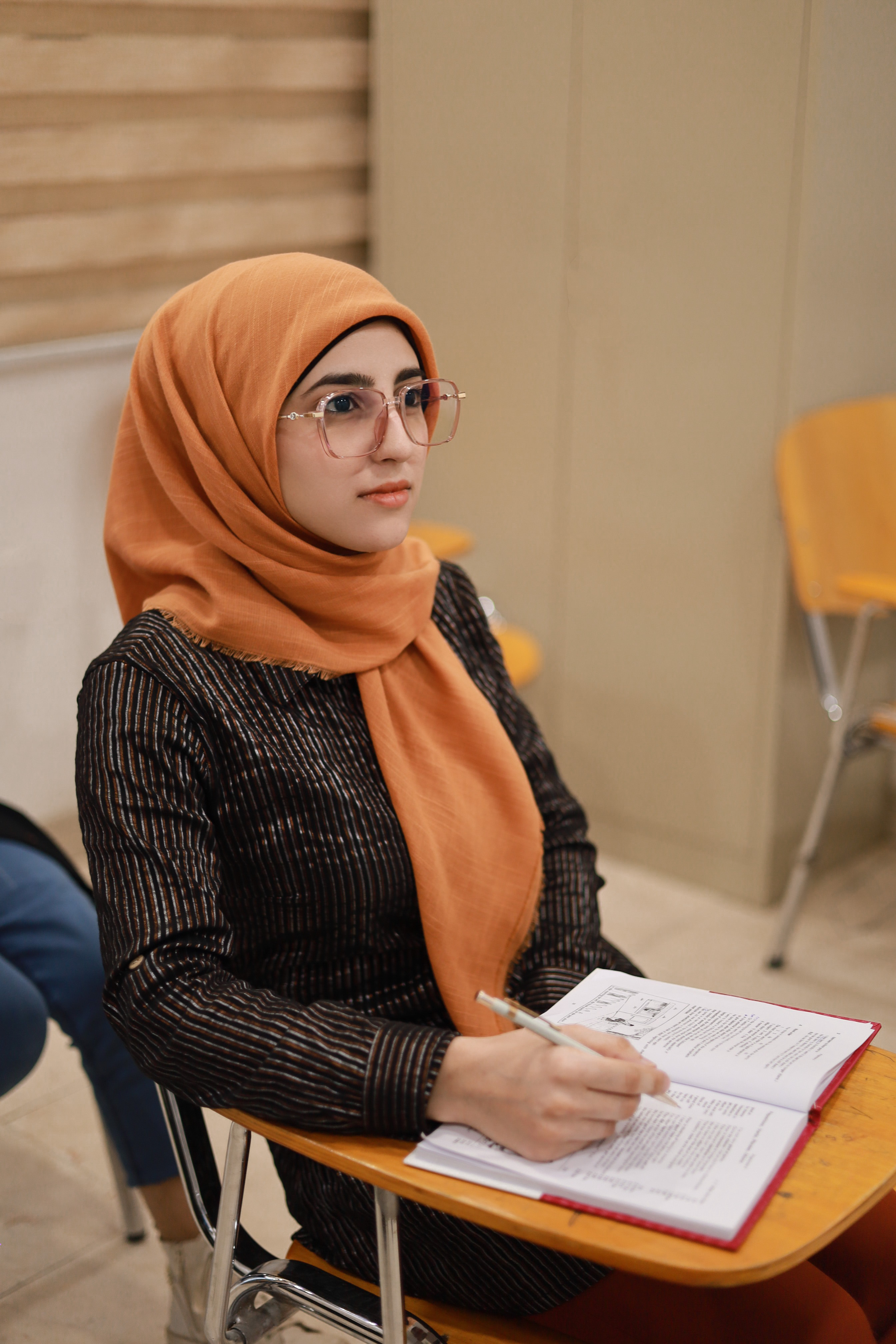 طالبة أثناء الكتابة بدفترها