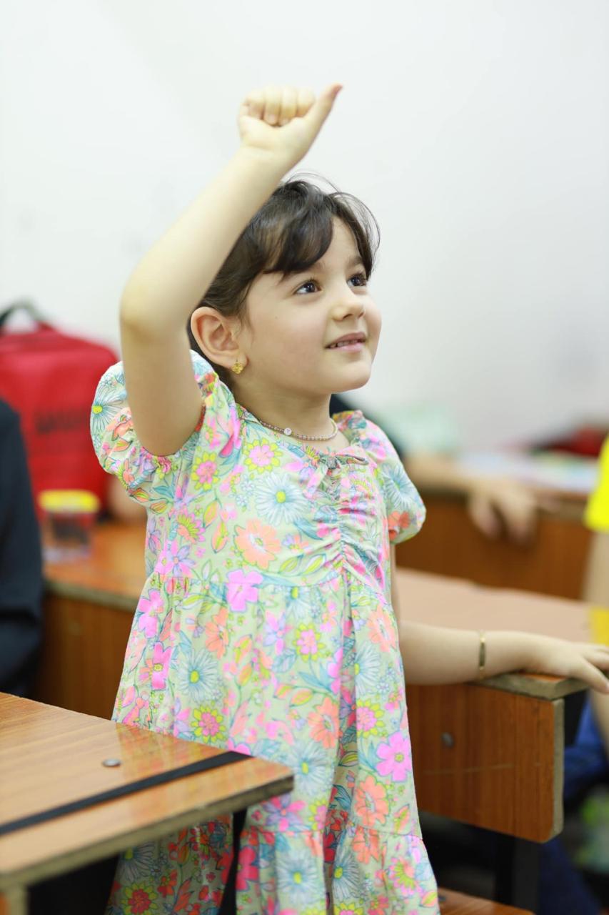 طالبة صغيرة ترفع يدها للمشاركة بالصف