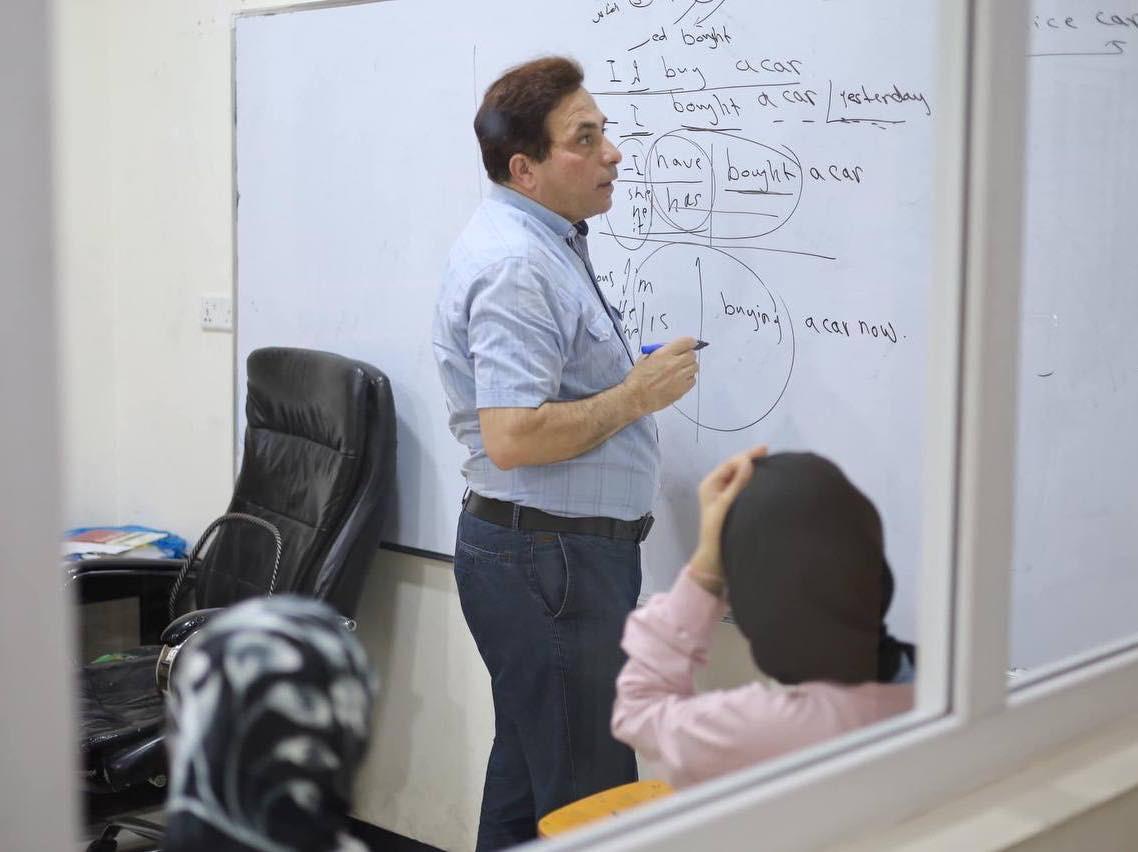 مدرّس يشرح قواعد اللغة الإنجليزية على السبورة